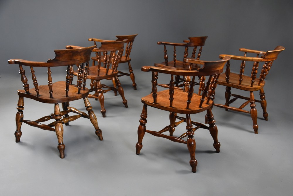 A set of six mid 19th century wooden smokers bow Windsor chairs with curved crest rails, turned spindles, shaped seats, and turned legs with stretchers. View V