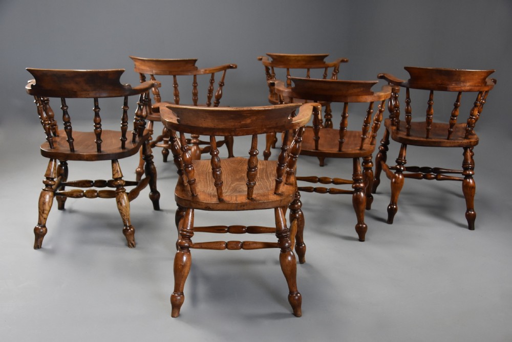 A set of six mid 19th century wooden smokers bow Windsor chairs with curved crest rails, turned spindles, shaped seats, and turned legs with stretchers. View VI