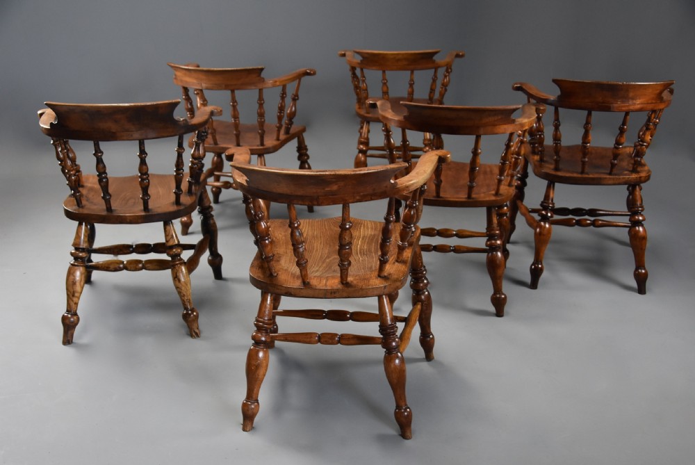 A set of six mid 19th century wooden smokers bow Windsor chairs with curved crest rails, turned spindles, shaped seats, and turned legs with stretchers. View VII