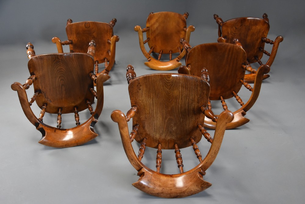 A set of six mid 19th century wooden smokers bow Windsor chairs with curved crest rails, turned spindles, shaped seats, and turned legs with stretchers. View IX