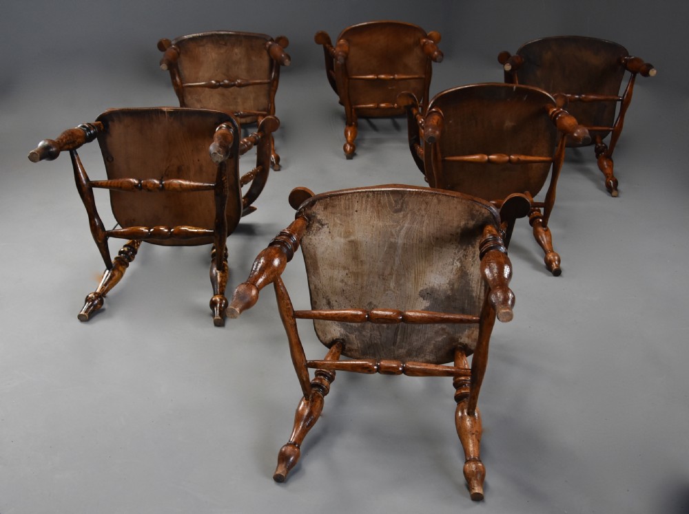A set of six mid 19th century wooden smokers bow Windsor chairs with curved crest rails, turned spindles, shaped seats, and turned legs with stretchers. View X