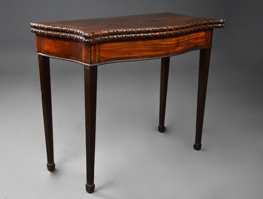 An 18th-century mahogany fold-over card table featuring a serpentine front, carved egg-and-dart rim moulding, and straight fluted legs. View IV