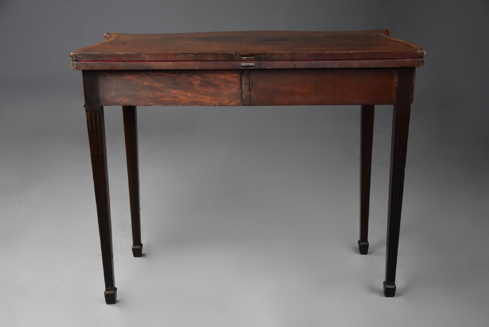 An 18th-century mahogany fold-over card table featuring a serpentine front, carved egg-and-dart rim moulding, and straight fluted legs. View XV