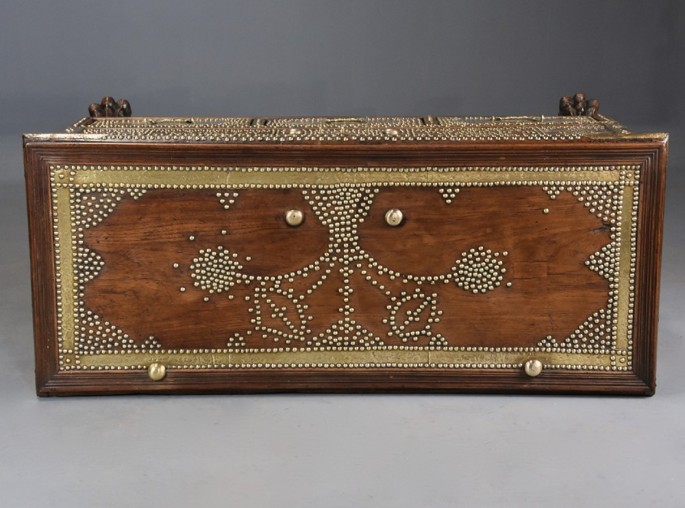 A mid-19th century Zanzibar wooden chest featuring intricate brass studding, pierced brass plates, three lower drawers, and carved feet. View XIII
