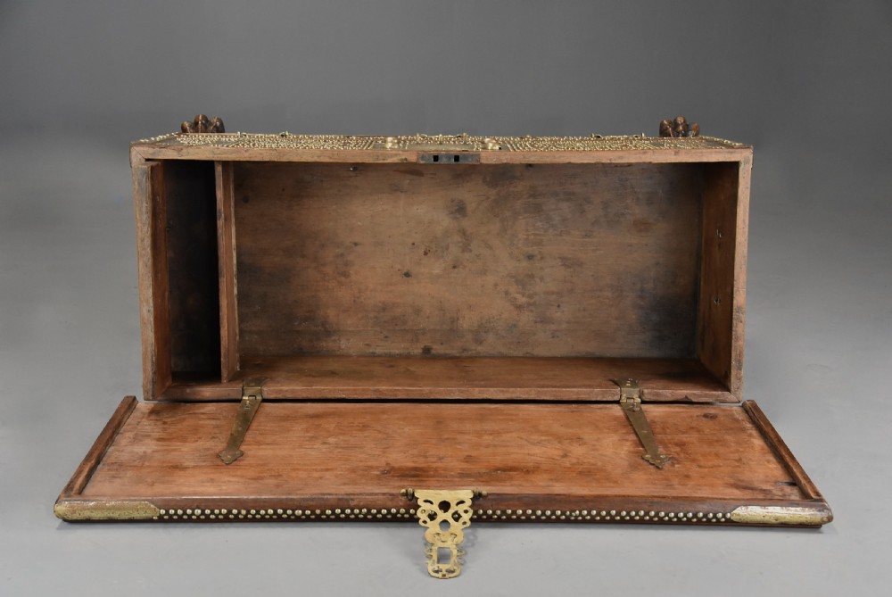 A mid-19th century Zanzibar wooden chest featuring intricate brass studding, pierced brass plates, three lower drawers, and carved feet. View XIV