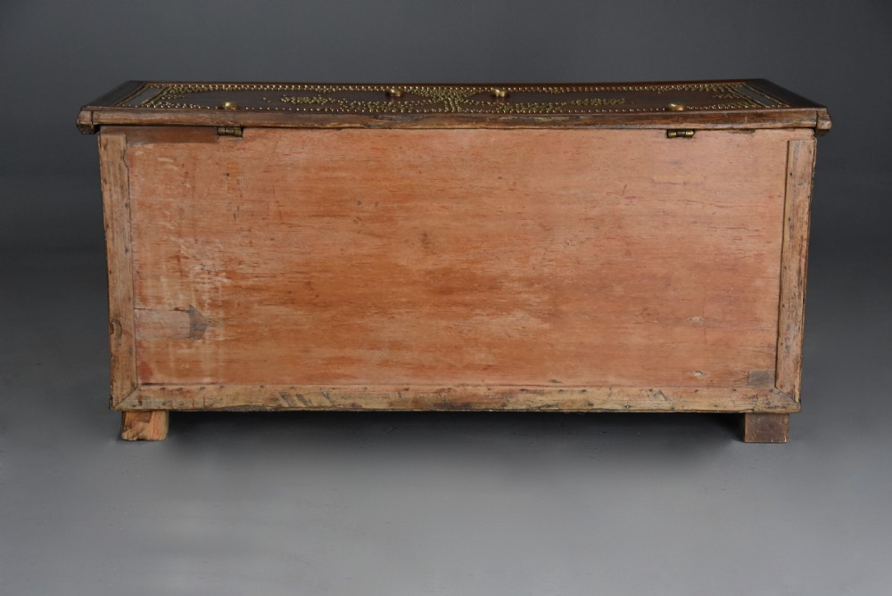 A mid-19th century Zanzibar wooden chest featuring intricate brass studding, pierced brass plates, three lower drawers, and carved feet. View XV