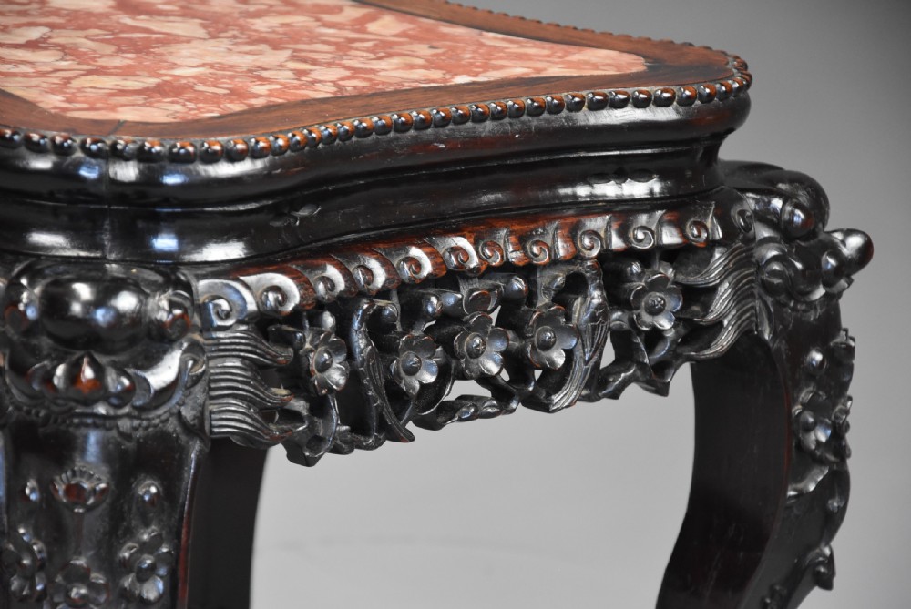 A late 19th-century Chinese dark hardwood low table with a beaded edge, shaped pink marble inset top, pierced carved apron, and cabriole legs terminating in claw feet. View V