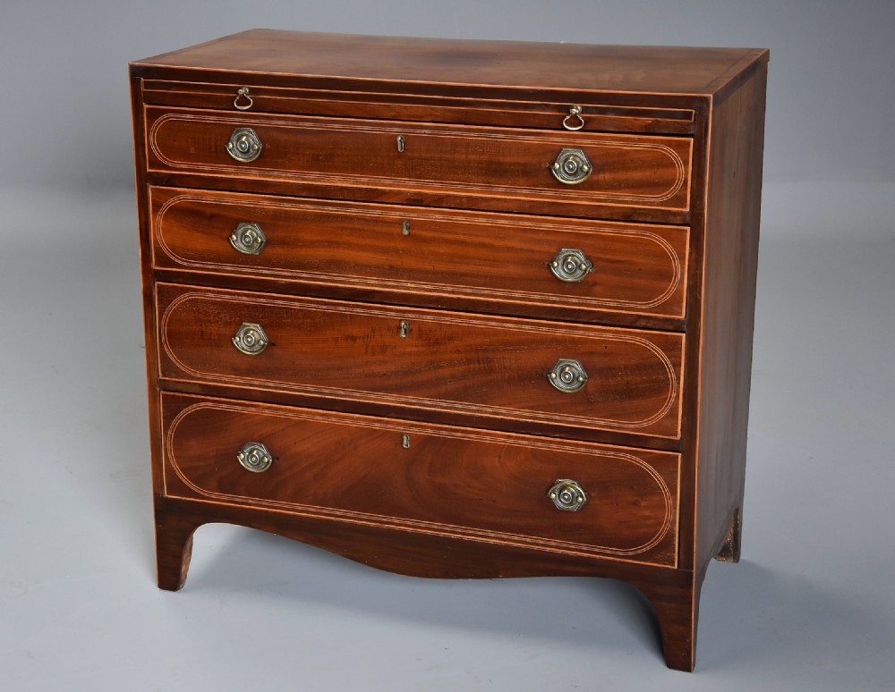 A late nineteenth-century mahogany chest of drawers featuring four graduated drawers with satinwood string inlay, octagonal brass handles, a brushing slide, and splayed bracket feet.