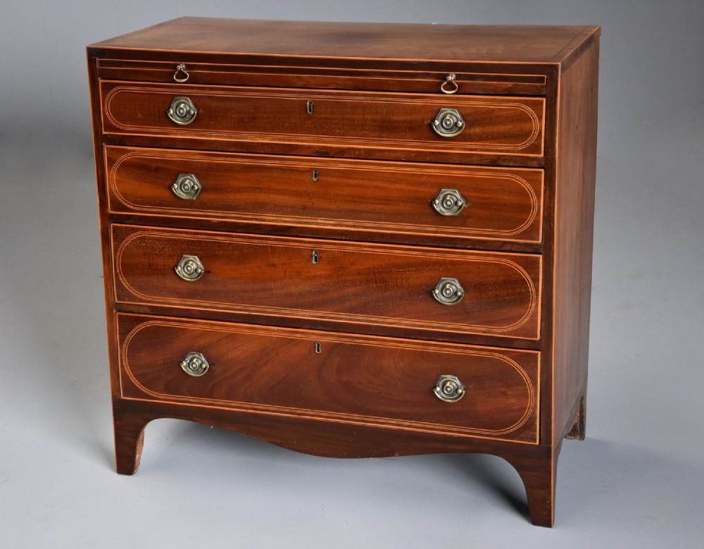 A late nineteenth-century mahogany chest of drawers featuring four graduated drawers with satinwood string inlay, octagonal brass handles, a brushing slide, and splayed bracket feet. View V