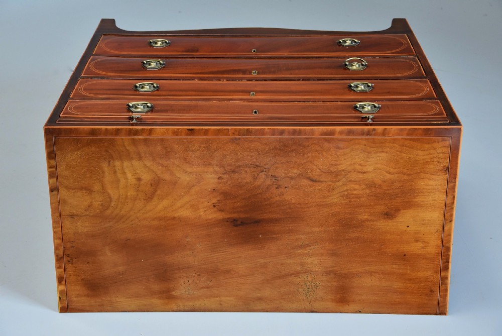 A late nineteenth-century mahogany chest of drawers featuring four graduated drawers with satinwood string inlay, octagonal brass handles, a brushing slide, and splayed bracket feet. View X