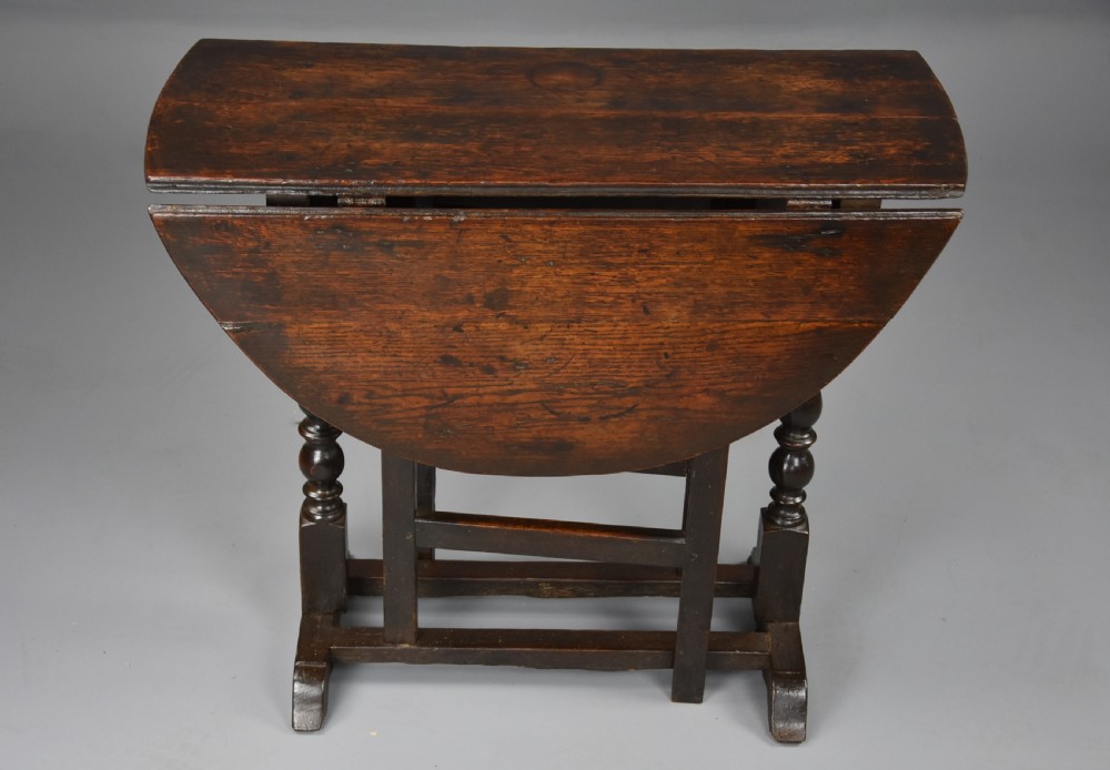 A seventeenth-century dark oak gateleg table shown with both drop-down leaves extended to form an oval tabletop supported on turned legs. View VIII