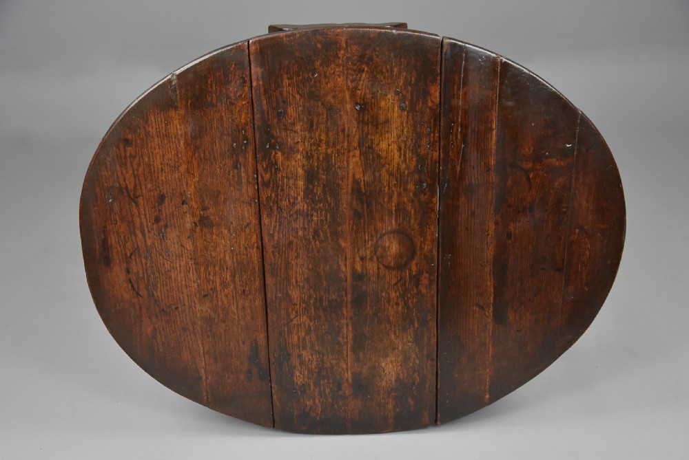 A seventeenth-century dark oak gateleg table shown with both drop-down leaves extended to form an oval tabletop supported on turned legs. View XI