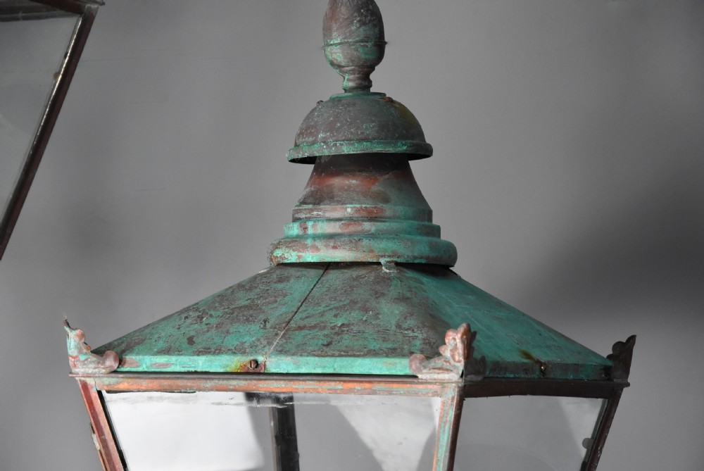 A pair of wall-mounted copper Windsor street lanterns featuring aged verdigris canopies, clear glass panels, and black spiral twist brackets. View VII