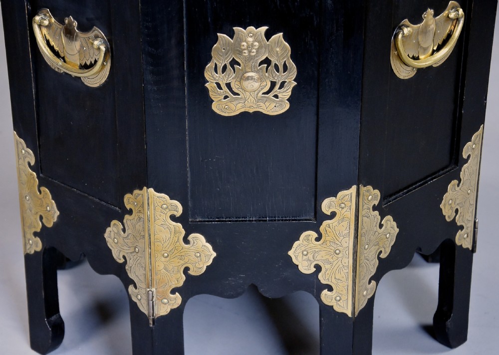 An octagonal ebonised black wood occasional table adorned with etched brass corner mounts, side handles, and a central pierced brass top medallion. View XI