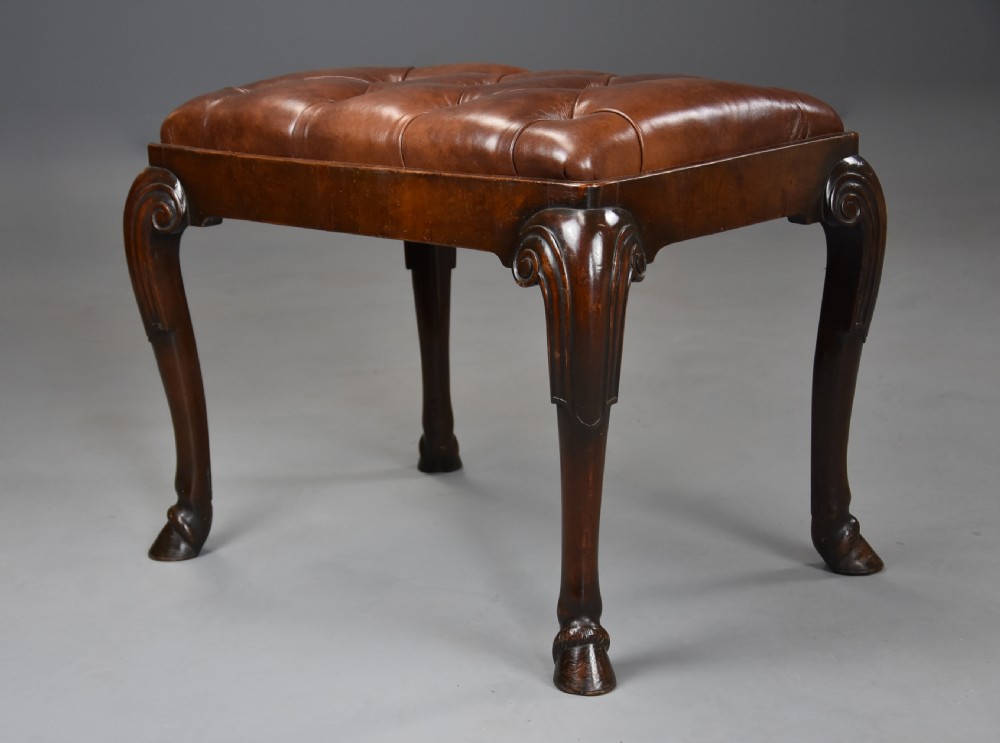 A late 19th-century Queen Anne style walnut stool featuring a deep-buttoned brown leather seat and carved cabriole legs with hoof feet. View II