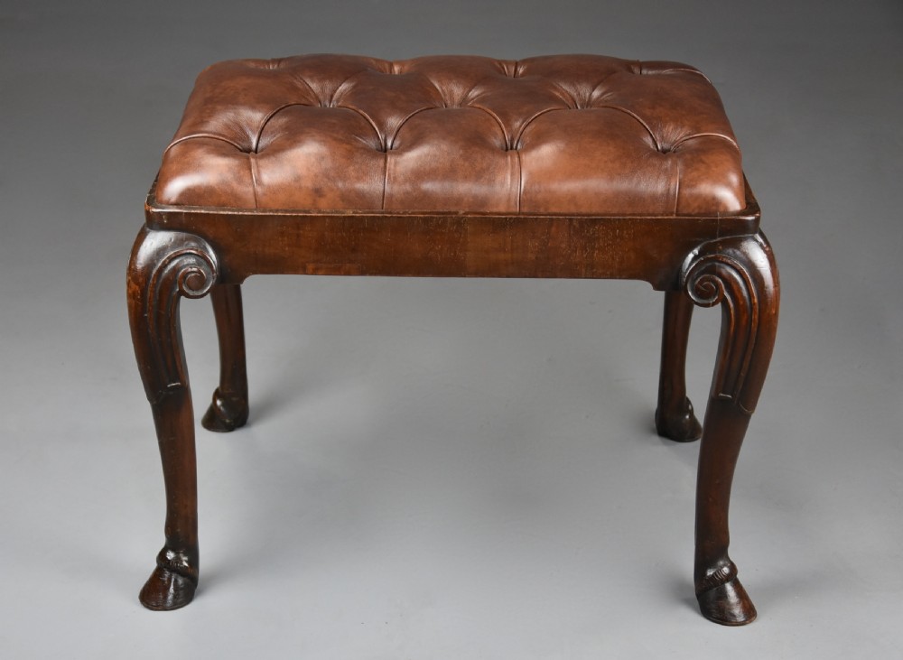 A late 19th-century Queen Anne style walnut stool featuring a deep-buttoned brown leather seat and carved cabriole legs with hoof feet. View VIII