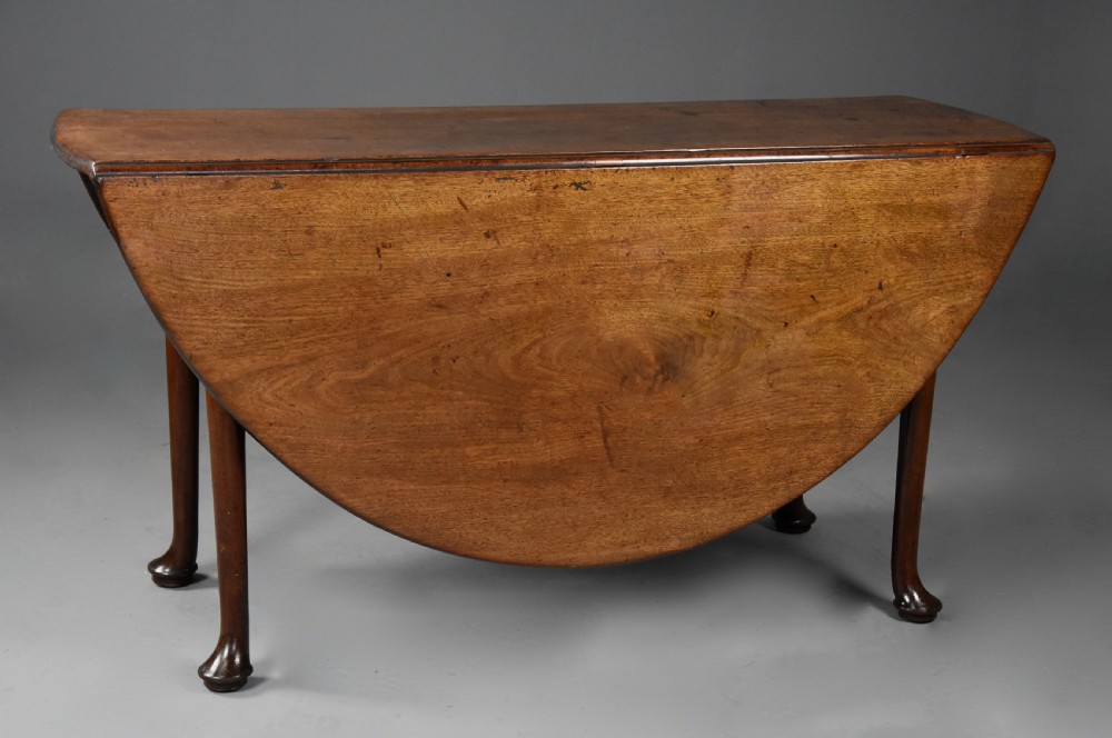 A mid-18th-century solid walnut drop-leaf dining table supported by cabriole legs with pad feet.