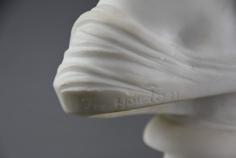 A white Carrara marble portrait bust depicting a young child with a floral wreath in curly hair, mounted on a turned circular pedestal base. View XII