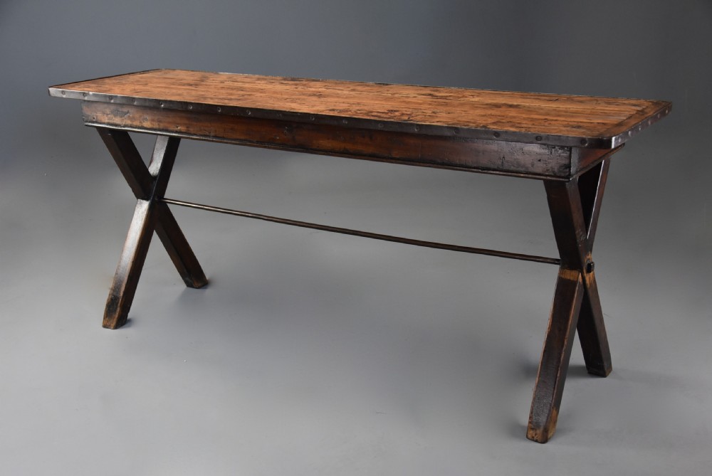An early 19th-century sycamore tavern table featuring an X-frame trestle base, plank top, and metal stretcher rod. View II