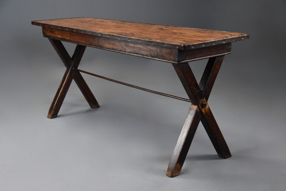 An early 19th-century sycamore tavern table featuring an X-frame trestle base, plank top, and metal stretcher rod. View IV