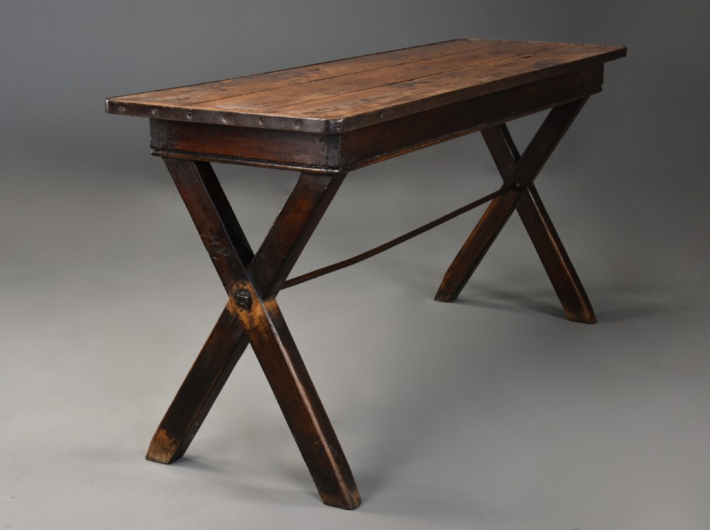 An early 19th-century sycamore tavern table featuring an X-frame trestle base, plank top, and metal stretcher rod. View VI