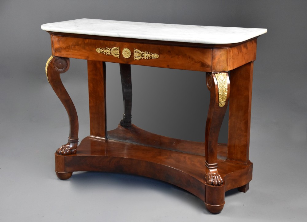 An early nineteenth-century French Charles X mahogany console table with a white marble top, curved front legs ending in paw feet, gilt-bronze mounts, and a mirrored back above a concave base. View II