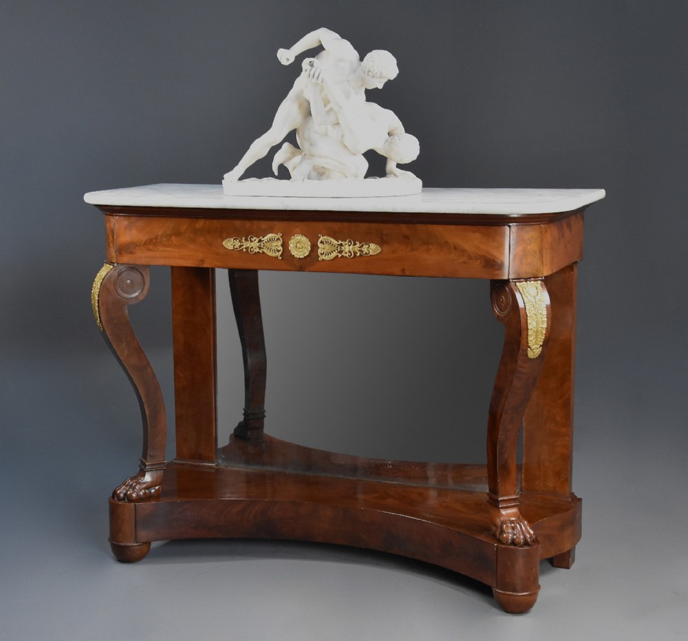 An early nineteenth-century French Charles X mahogany console table with a white marble top, curved front legs ending in paw feet, gilt-bronze mounts, and a mirrored back above a concave base.