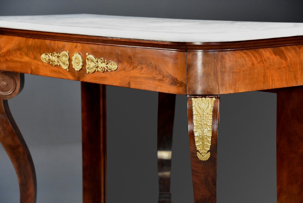 An early nineteenth-century French Charles X mahogany console table with a white marble top, curved front legs ending in paw feet, gilt-bronze mounts, and a mirrored back above a concave base. View VII