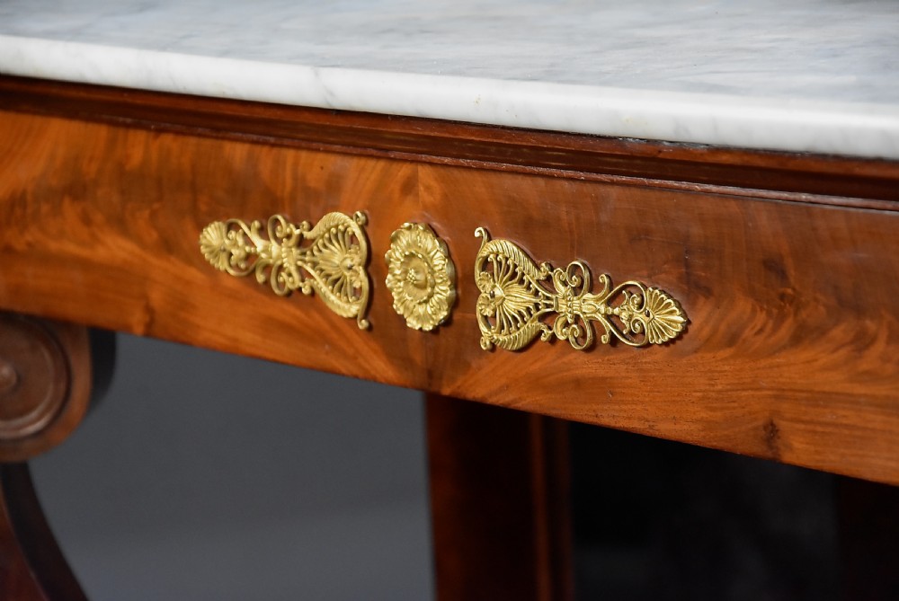 An early nineteenth-century French Charles X mahogany console table with a white marble top, curved front legs ending in paw feet, gilt-bronze mounts, and a mirrored back above a concave base. View VIII