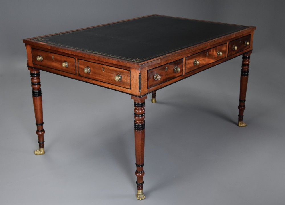 A Regency mahogany writing table featuring a dark leather insert, six drawers with brass knobs, and reeded turned legs with brass paw feet. View II