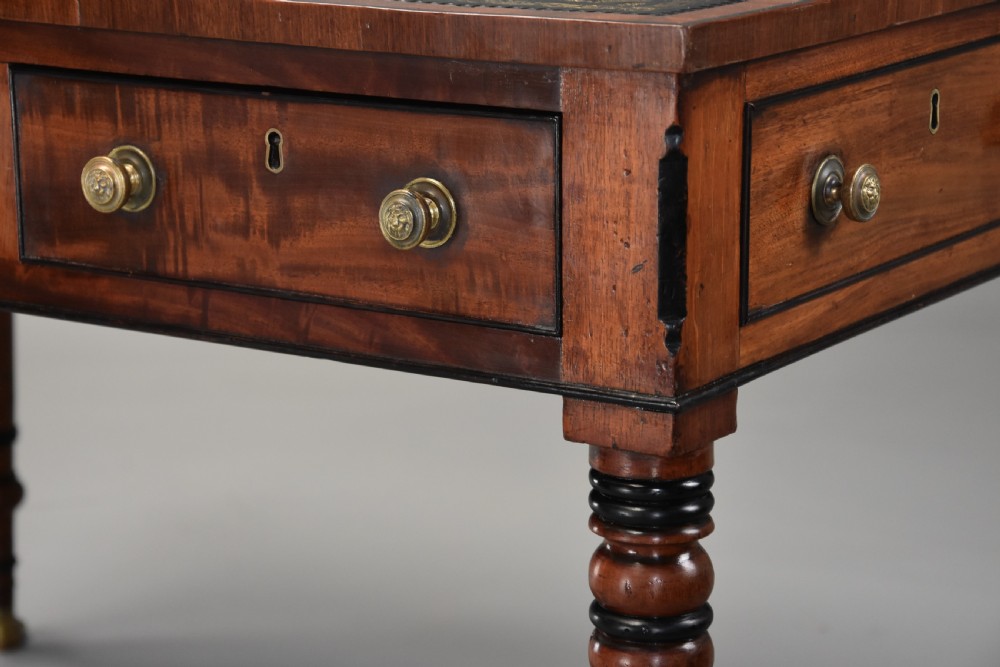 A Regency mahogany writing table featuring a dark leather insert, six drawers with brass knobs, and reeded turned legs with brass paw feet. View VIII