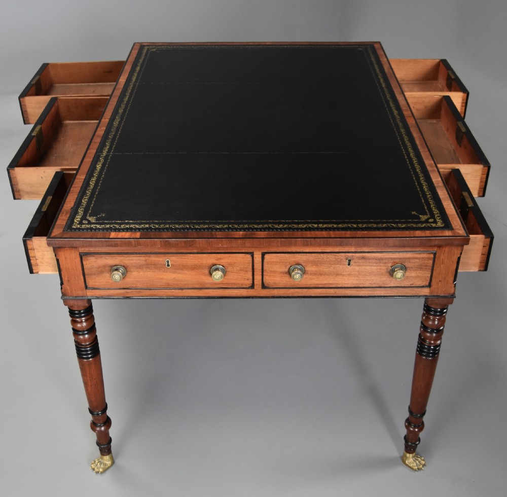 A Regency mahogany writing table featuring a dark leather insert, six drawers with brass knobs, and reeded turned legs with brass paw feet. View X