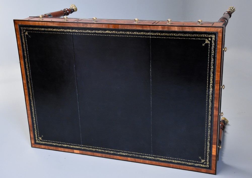 A Regency mahogany writing table featuring a dark leather insert, six drawers with brass knobs, and reeded turned legs with brass paw feet. View XI
