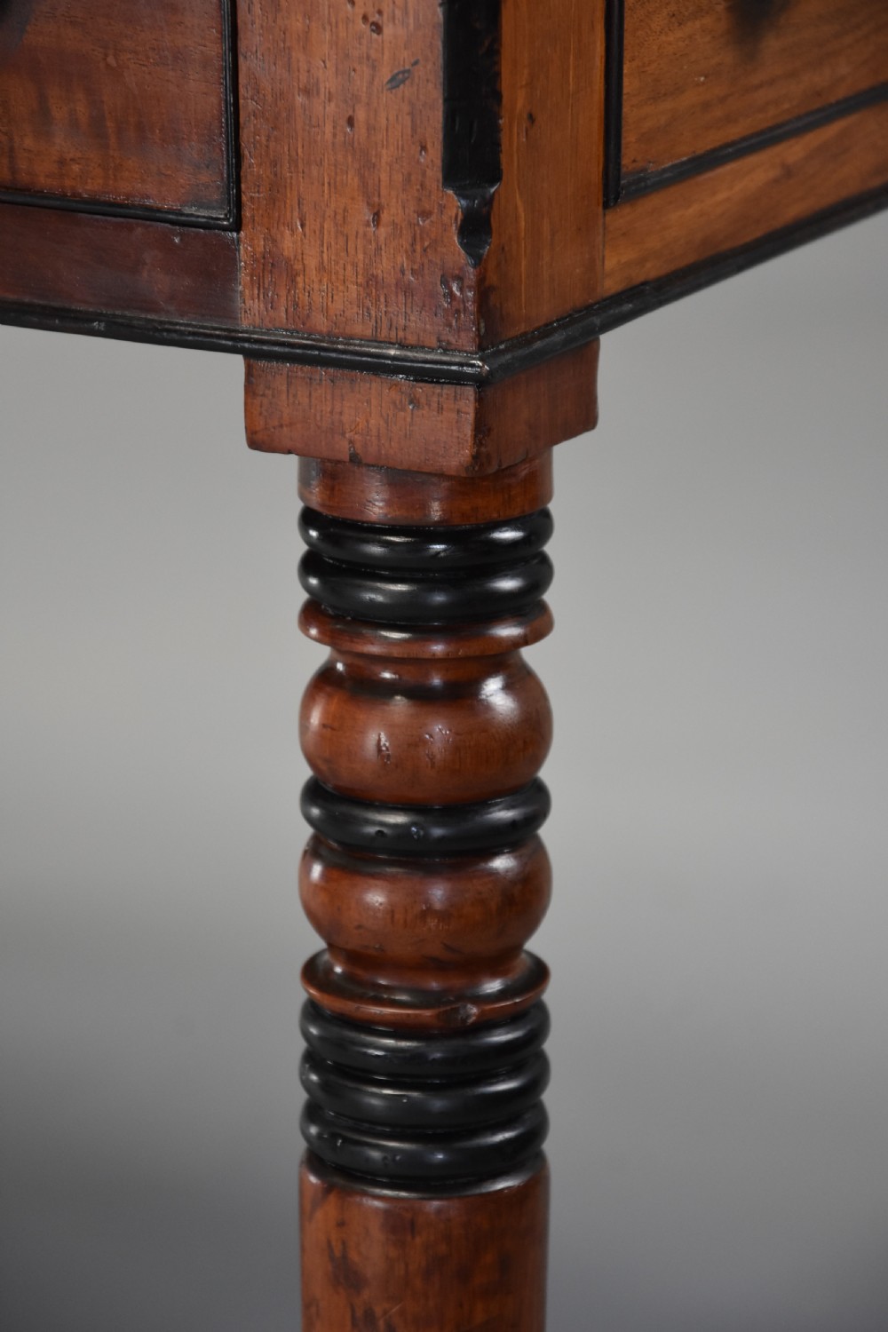 A Regency mahogany writing table featuring a dark leather insert, six drawers with brass knobs, and reeded turned legs with brass paw feet. View XII