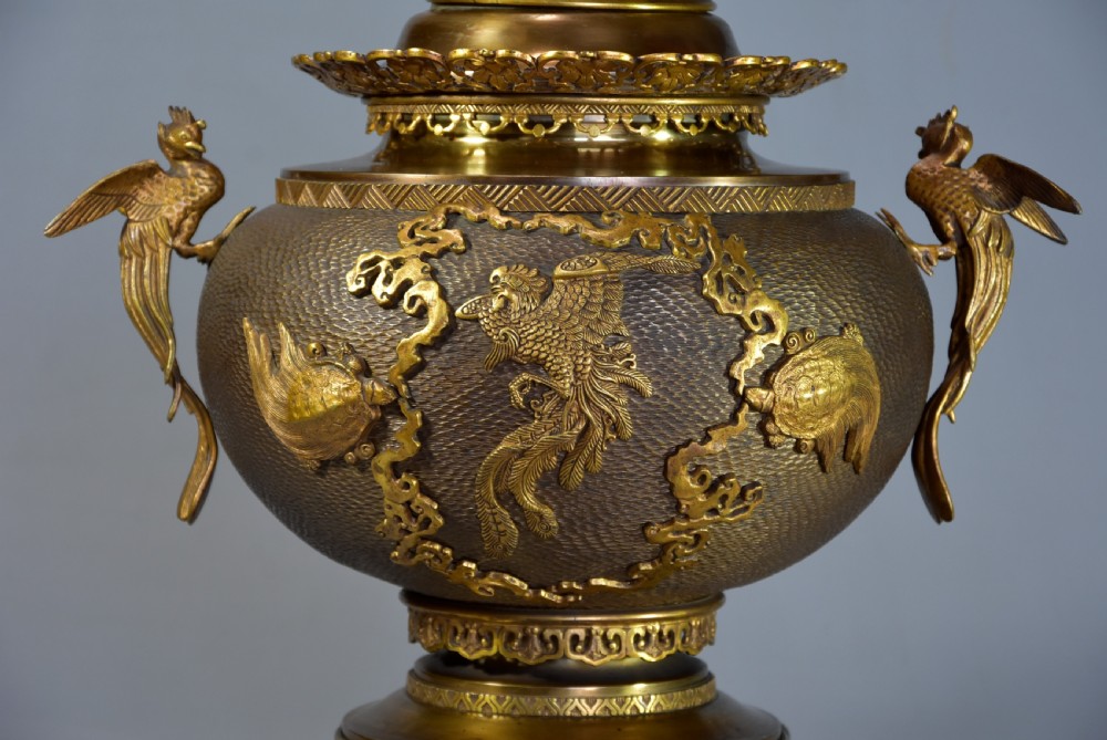 A late nineteenth-century three-piece French Japonisme bronze garniture set featuring a central incense burner flanked by two tall urns, decorated with gilt dragon reliefs and supported on elephant head feet. View III