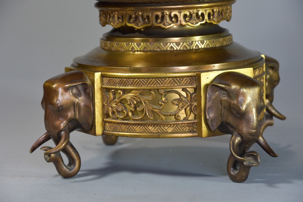 A late nineteenth-century three-piece French Japonisme bronze garniture set featuring a central incense burner flanked by two tall urns, decorated with gilt dragon reliefs and supported on elephant head feet. View VI