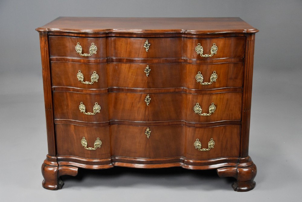 An 18th-century mahogany oxbow commode with four drawers, ornate brass bail handles, and prominent shaped feet. View IV