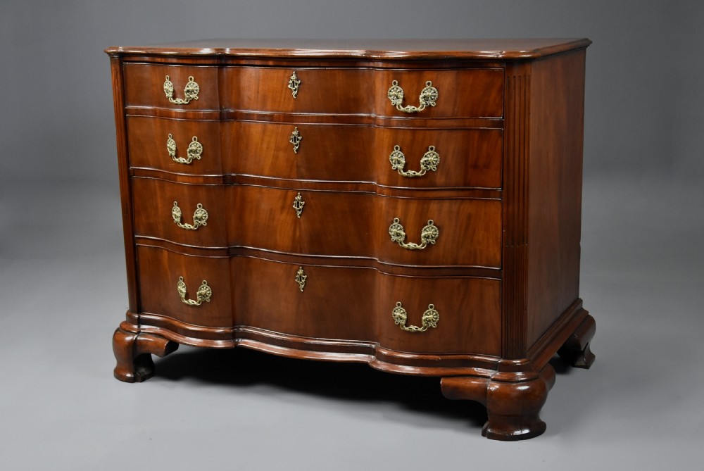 An 18th-century mahogany oxbow commode with four drawers, ornate brass bail handles, and prominent shaped feet. View V