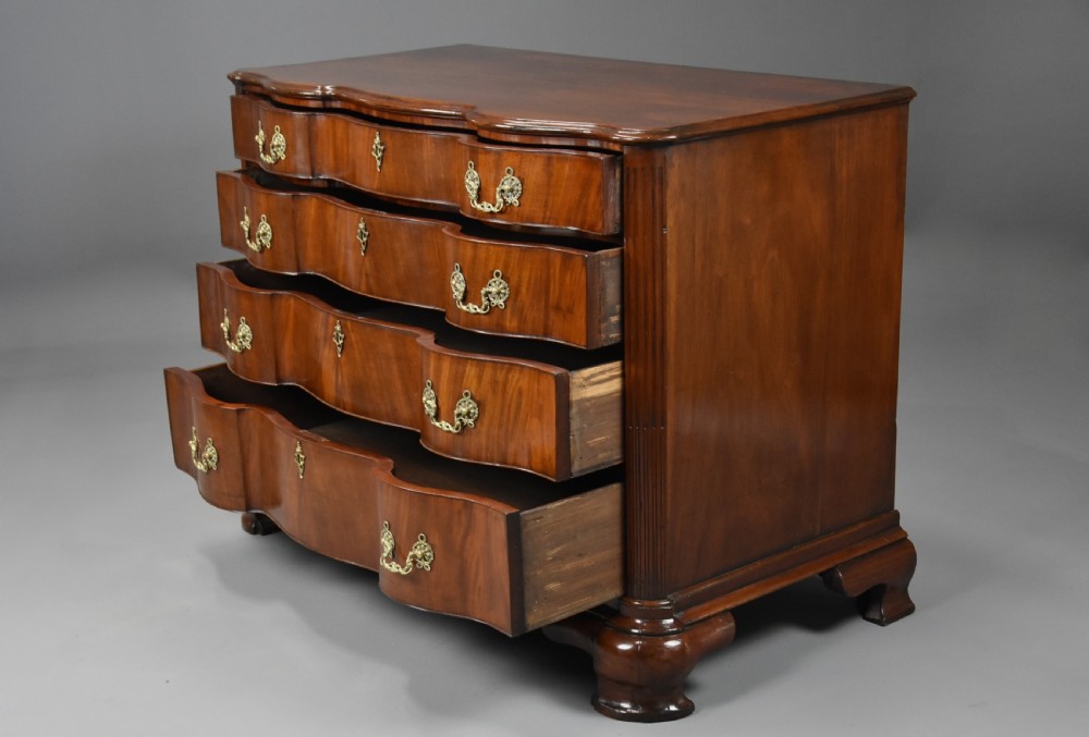 An 18th-century mahogany oxbow commode with four drawers, ornate brass bail handles, and prominent shaped feet. View X