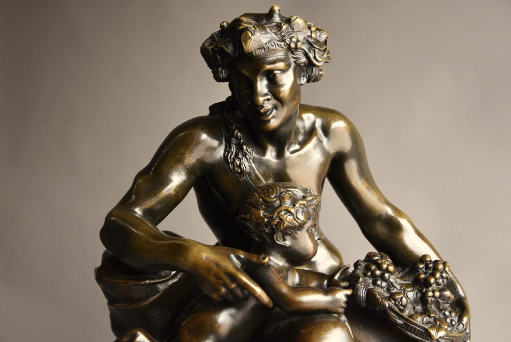 A mid-19th century dark patinated bronze sculpture depicting a satyr seated with two young fauns, mounted on a round reddish marble base. View II