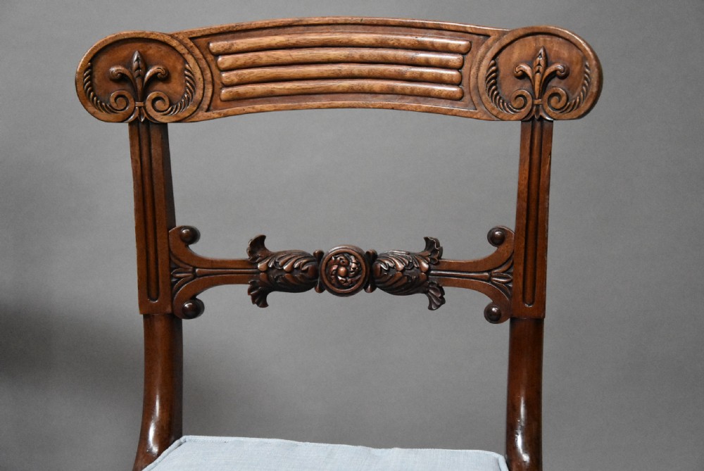 A set of eight antique Regency mahogany dining chairs featuring reeded top rails, carved mid-rails, scrolled armrests, and pale blue upholstered seats. View VII