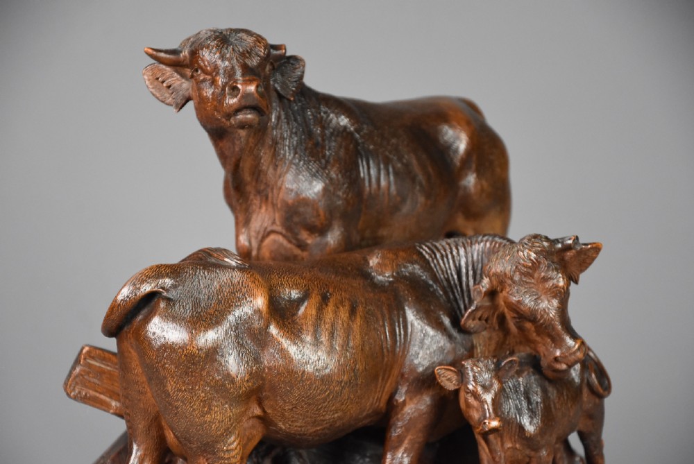A late nineteenth-century dark linden wood sculpture depicting a bull, cow, and calf standing on a naturalistic base with carved edelweiss motifs. View III
