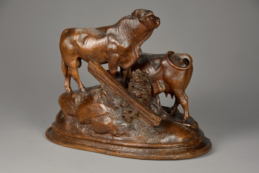 A late nineteenth-century dark linden wood sculpture depicting a bull, cow, and calf standing on a naturalistic base with carved edelweiss motifs. View IX