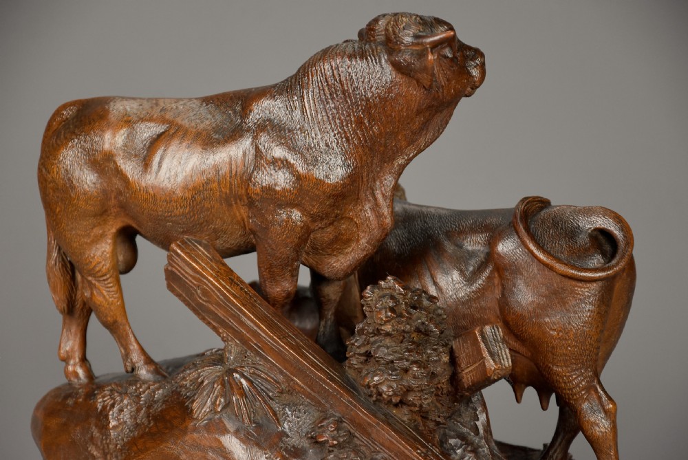 A late nineteenth-century dark linden wood sculpture depicting a bull, cow, and calf standing on a naturalistic base with carved edelweiss motifs. View X