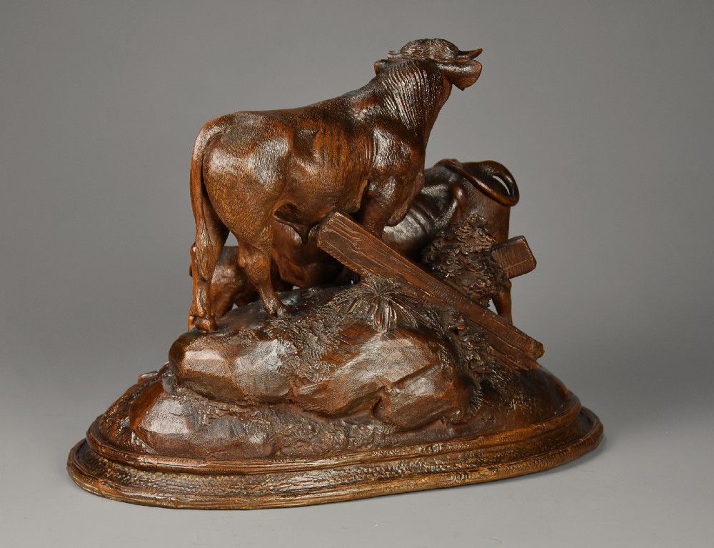 A late nineteenth-century dark linden wood sculpture depicting a bull, cow, and calf standing on a naturalistic base with carved edelweiss motifs. View XI