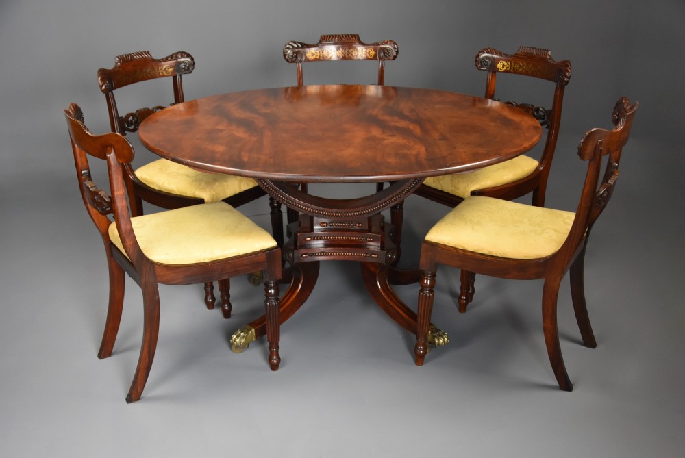 An early nineteenth-century circular mahogany centre table shown tilted upright on a central pedestal with four splayed legs terminating in brass paw castors. View VI