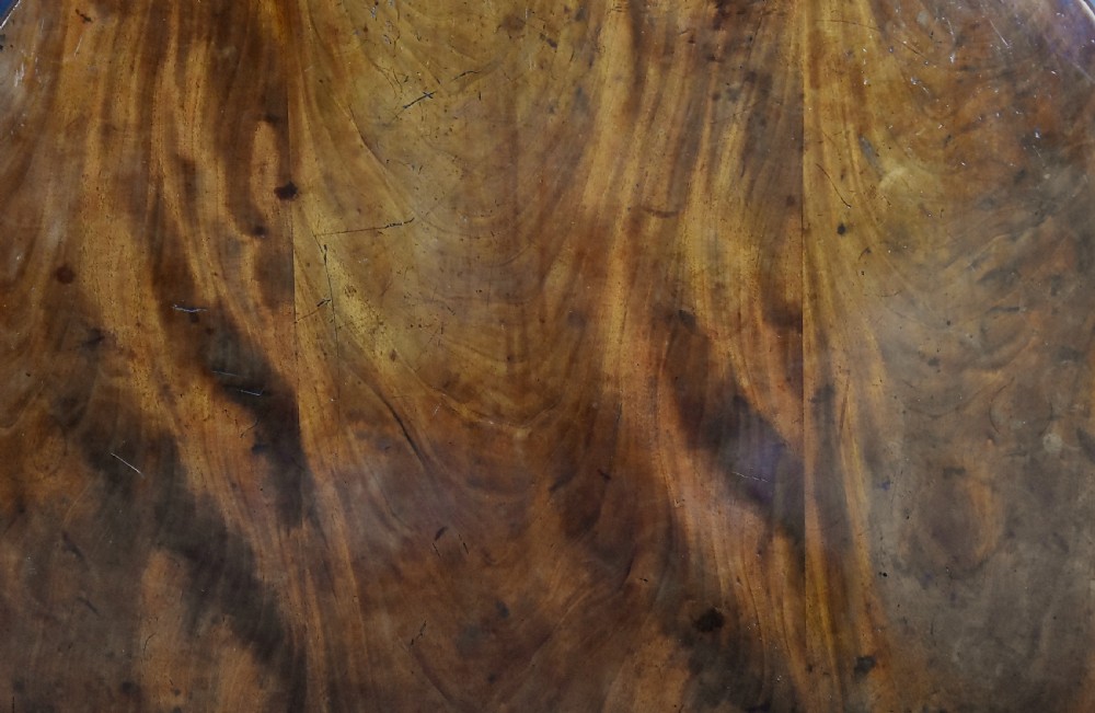 An early nineteenth-century circular mahogany centre table shown tilted upright on a central pedestal with four splayed legs terminating in brass paw castors. View XI