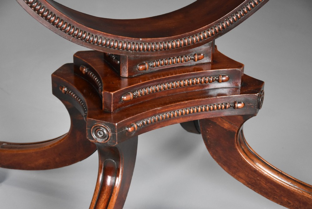 An early nineteenth-century circular mahogany centre table shown tilted upright on a central pedestal with four splayed legs terminating in brass paw castors. View XII