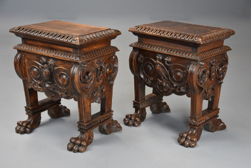 A pair of carved warm brown walnut stools with gadrooned tops, central bird reliefs, scrollwork aprons, and paw feet. View II