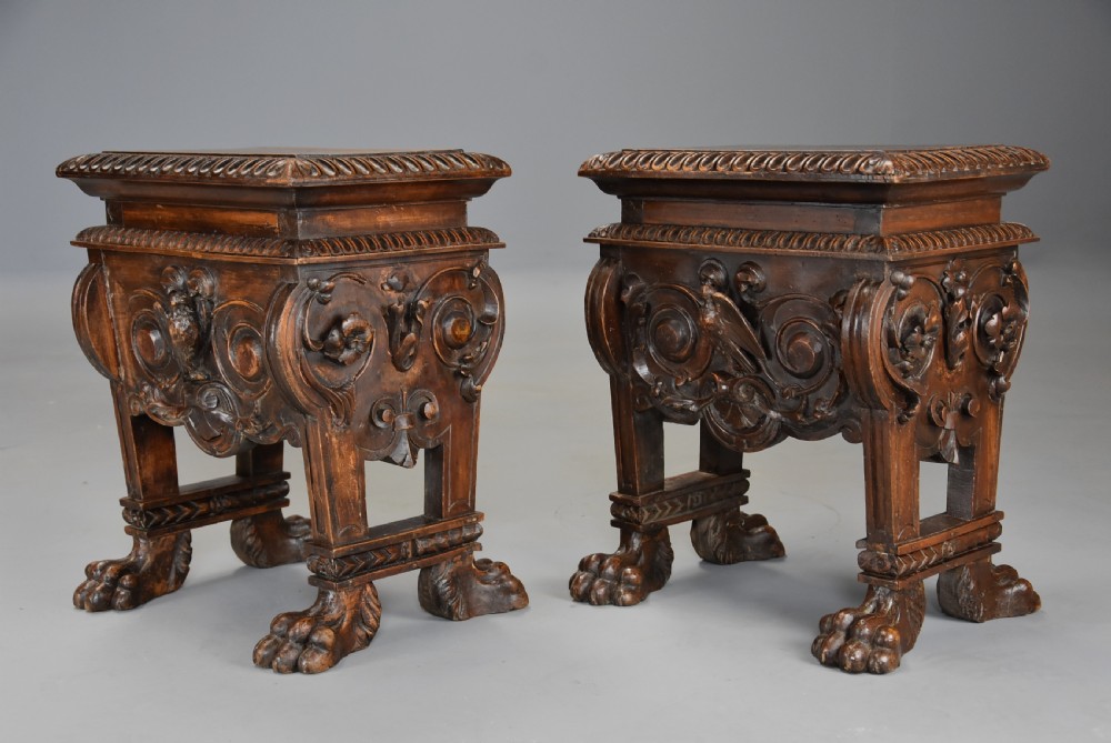 A pair of carved warm brown walnut stools with gadrooned tops, central bird reliefs, scrollwork aprons, and paw feet. View V